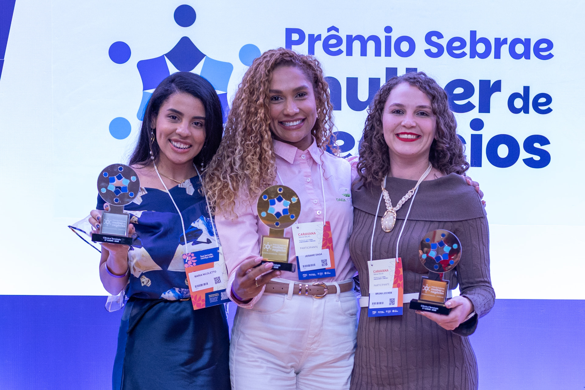 As três premiadas da categoria Ciência e Tecnologia do Prêmio Sebrae Mulher de Negócios 2026, com Josiane Daga ao centro segurando o troféu de 1º lugar.